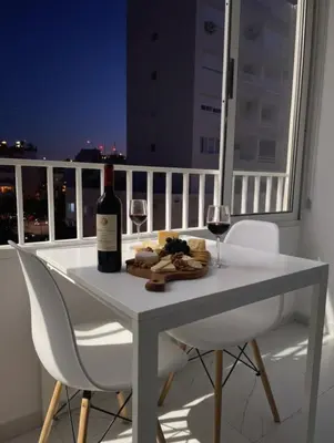 a white table with a bottle of wine and wine glasses at Marble Coast Studio Apartment in Larnaka