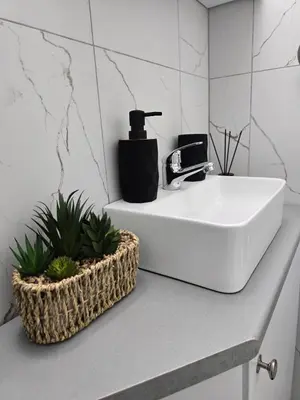 a bathroom sink with a black soap dispenser on it at Marble Coast Studio Apartment in Larnaka