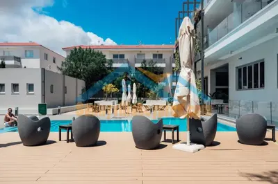 a pool with chairs and an umbrella in front of a building at SunnyVillas Suite Mythical GYM Swimming Pool S19 in Paralimni