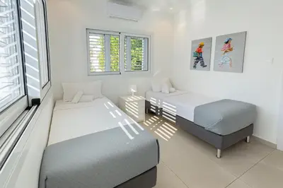 two beds in a room with white walls and windows at Seaside Sunrise Familly Villa in Paralimni