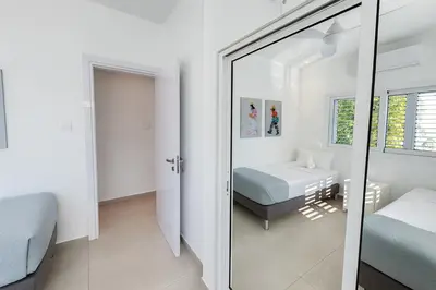 a white bedroom with a mirror and a bed at Seaside Sunrise Familly Villa in Paralimni