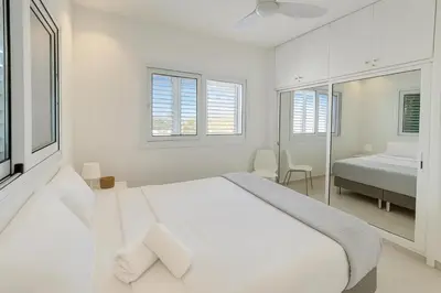 a white bedroom with a large white bed and windows at Seaside Sunrise Familly Villa in Paralimni