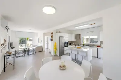 a white kitchen and living room with a white table and chairs at Seaside Sunrise Familly Villa in Paralimni