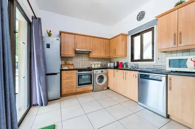 a kitchen with wooden cabinets and a washer and dryer at Sunnyside Family Villa in Protaras