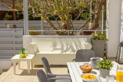 a patio with a table and chairs and trees at Pantaros Luxury Villas with pool in Paralimni