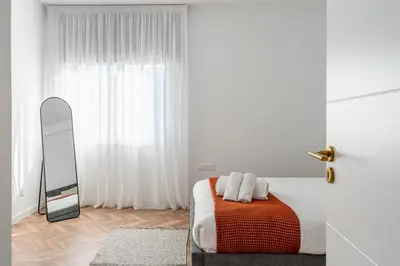 a white bedroom with a bed and a mirror at Modern Luxury 2BR|Park View & Balcony in Nicosia