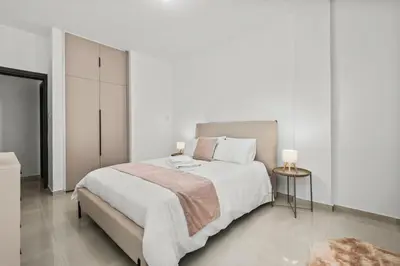 a white bedroom with a large bed and a table at Mnasiadou Suite 16 in Nicosia