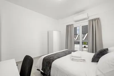 a white bedroom with a bed and a window at Mnasiadou Suite 16 in Nicosia