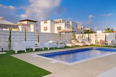 a swimming pool with white furniture and a building at Villa Esmeralda - Luxury Villa in Pernera in Paralimni