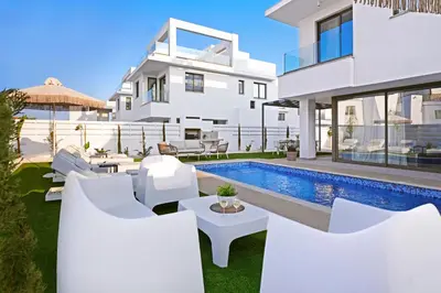 a white house with a swimming pool and white furniture at Villa Esmeralda - Luxury Villa in Pernera in Paralimni