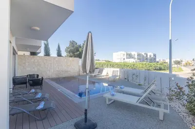 a swimming pool with an umbrella and lounge chairs next to a swimming pool at Mythical Blue Villas in Protaras