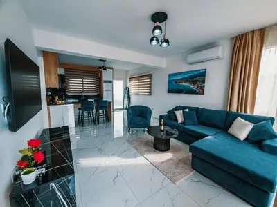 a living room with a blue couch and a kitchen at Chic Blue Apartment with Terrace in Paralimni