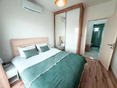 a bedroom with a large bed with a green blanket at Chic Sunset Apartment with Terrace in Protaras