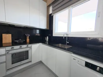 a kitchen with white cabinets and a sink and a window at Chic Sunset Apartment with Terrace in Protaras
