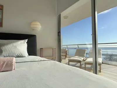 a bedroom with a bed and a balcony with chairs at Breathtaking Sea and Marina View City Center 2 bdr in Larnaka