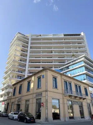 a large white building with cars parked in front of it at Breathtaking Sea and Marina View City Center 2 bdr in Larnaka