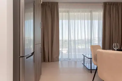 a kitchen with a refrigerator and a table and a window at BlueStar Limassol Suites in Limassol