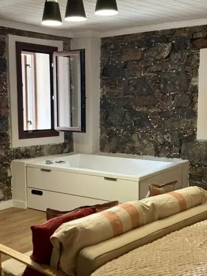 a bath tub in a room with a stone wall at Aprosmeno Jacuzzi House 6 in Agros
