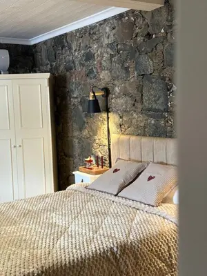 a bedroom with a bed with a stone wall at Aprosmeno Jacuzzi House 6 in Agros
