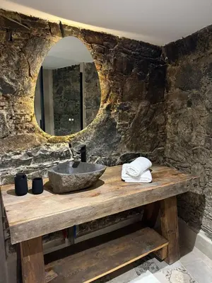 a stone bathroom with a sink and a mirror at Aprosmeno Jacuzzi House 6 in Agros
