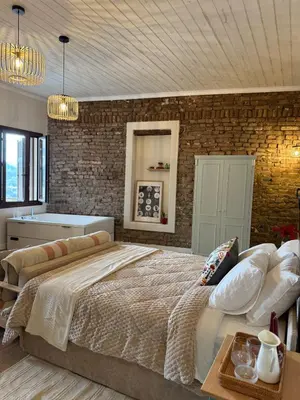 a bedroom with a large bed and a brick wall at Aprosmeno Jacuzzi House 7 in Agros