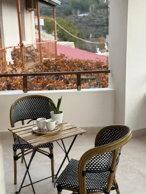 a table and two chairs with cups on a balcony at Aprosmeno Jacuzzi House 7 in Agros