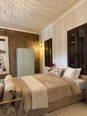 a bedroom with a large bed and a brick wall at Aprosmeno Jacuzzi House 7 in Agros