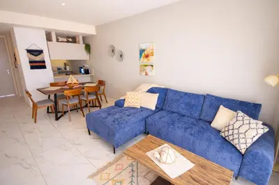 a living room with a blue couch and a table at Mythical Sands 2 - G in Aglantzia