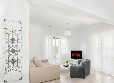 a white living room with a couch and a chair at Fig Tree Beach Villa Two in Paralimni