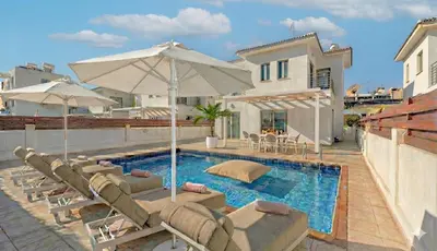 a swimming pool with lounge chairs and an umbrella at Fig Tree Beach Villa Two in Paralimni