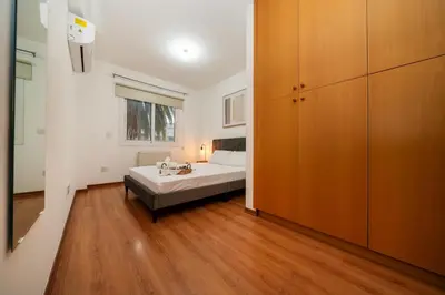 a bedroom with a bed and a large wooden cabinet at 2 bedroom flat in center in Nicosia