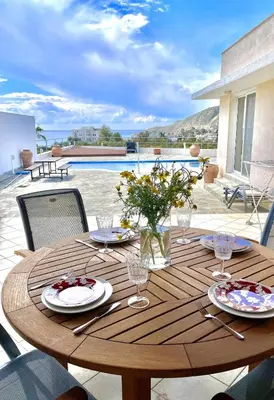 a wooden table with plates of food and flowers on it at Stunning villa with breathtaking sea view in Pissouri