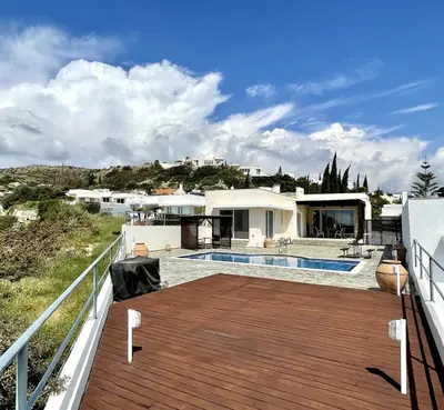 a house with a wooden deck and a swimming pool at Stunning villa with breathtaking sea view in Pissouri