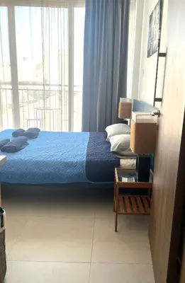 a bedroom with a blue bed and a large window at Unique 2 storey apt city centre in Larnaka