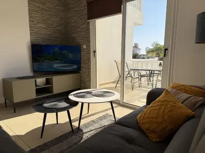 a living room with a couch and a tv and a table at Nissia Bella 1 - A in Ayia Napa