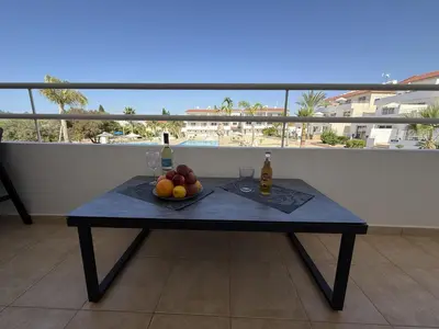 a table with a bowl of fruit and bottles of wine at Nissi 3, 1 -B in Ayia Napa