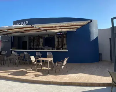 a patio with tables and chairs and a blue wall at Sunrise 80 in Aglantzia
