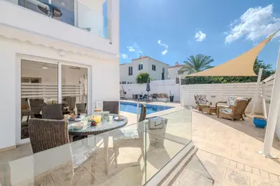 a villa with a swimming pool and a dining room at Ayia Triada Beach Gardens in Protaras