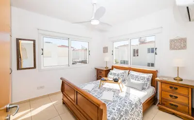 a bedroom with a bed and two windows at Ayia Triada Beach Gardens in Protaras