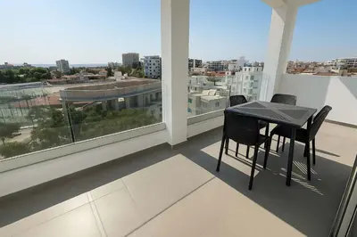 a table and chairs on a balcony with a view of a city at Modern 1BR with City View in Central Larnaca in Larnaka