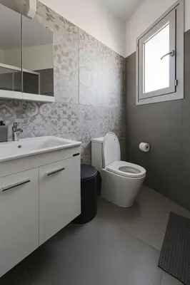 a bathroom with a toilet and a sink and a window at Modern 1BR with City View in Central Larnaca in Larnaka