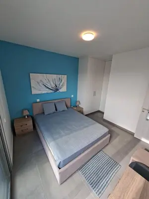 a bedroom with a large bed with a blue wall at Luxury central 1BR with city view in Larnaka