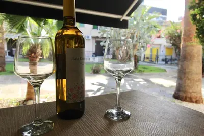 a bottle of wine and two wine glasses on a table at Cozy flat by the sea with big pool tourist area in Limassol