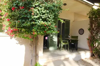 a patio with a table and a plant with red flowers at Cozy flat by the sea with big pool tourist area in Limassol