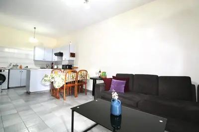 a living room and kitchen with a couch and a table at Cozy flat by the sea with big pool tourist area in Limassol