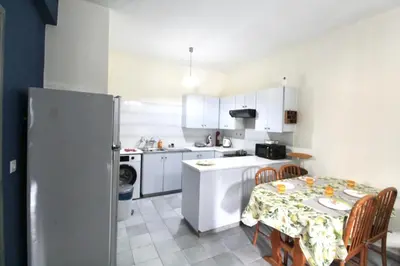 a small kitchen with a table and a refrigerator at Cozy flat by the sea with big pool tourist area in Limassol