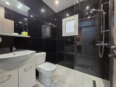 a black tiled bathroom with a toilet and a shower at Pop Art Residence by Staycom in Nicosia