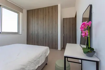 a bedroom with a bed and a table with a plant on it at BlueBell Limassol Suites in Limassol