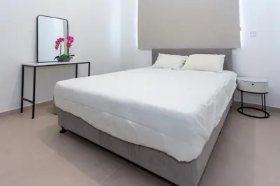 a bedroom with a large white bed and a mirror at BlueBell Limassol Suites in Limassol