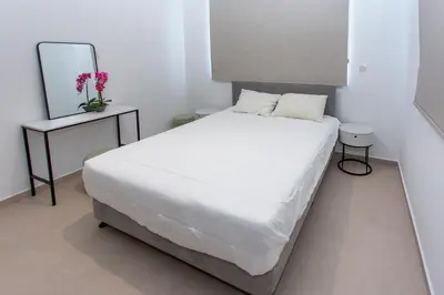 a bedroom with a white bed and a mirror at BlueBell Limassol Suites in Limassol